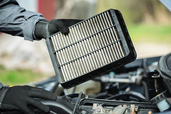 Technician removing dirty air filter from engine bay