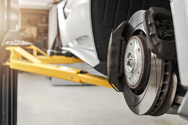 car on a lift with wheels removed, showing brakes