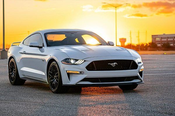 White Ford Mustang parked in front of sunset