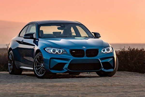 Blue BMW M2 parked in front of ocean